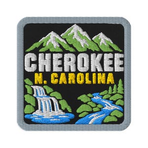 Puede incluir: Un parche bordado cuadrado con fondo negro que muestra montañas verdes con picos nevados blancos. El texto CHEROKEE está en blanco y N. CAROLINA en amarillo. Una cascada blanca y un río azul fluyen a través de árboles verdes.