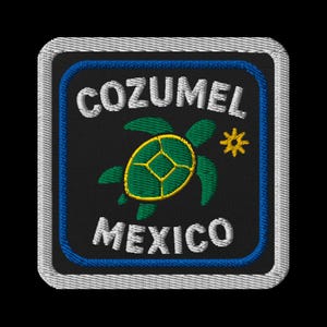 Op de afbeelding: Geborduurde patch met de tekst "COZUMEL MEXICO" in het wit, en een groen en geel schildpadontwerp. De patch heeft een zwarte achtergrond met een blauwe rand en een witte gestikte rand.