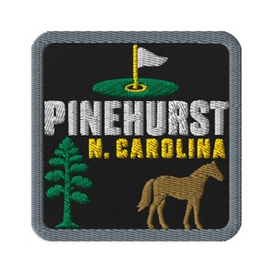 Puede incluir: Un parche bordado cuadrado con fondo negro y borde gris. Presenta una bandera de golf blanca sobre un green, el texto PINEHURST en blanco, N. CAROLINA en amarillo, un pino verde y un caballo marrón de pie en la parte inferior derecha.