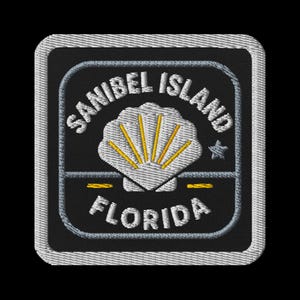 Puede incluir: Parche bordado con las palabras "SANIBEL ISLAND FLORIDA" en blanco, arqueadas arriba y abajo de un diseño de concha blanca con rayos amarillos. El parche es cuadrado con fondo negro y borde gris.