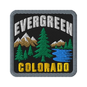 May include: A square embroidered patch with a black background and a gray border. The text EVERGREEN is stitched in white at the top, and COLORADO is in yellow at the bottom. It features brown mountains, green pine trees, and a blue lake.