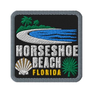 Könnte beinhalten: Ein quadratischer gestickter Aufnäher mit schwarzem Hintergrund und grauem Rand. Das Design zeigt einen weißen Sandstrand, blaue Meereswellen und grüne Palmen. Der Text lautet HORSESHOE BEACH in Weiß und FLORIDA in Gelb, mit einer Muschel.