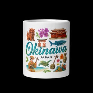 May include: White ceramic mug featuring colorful illustrations of Okinawa, Japan. The design includes a Shisa lion statue, purple flowers, a traditional building, a whale, and a woman playing a stringed instrument. The word "Okinawa" is written in teal and the word "Japan" is below it.