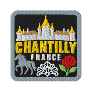 Peut inclure: Un écusson brodé carré avec une bordure grise sur fond noir. Il présente un château blanc et doré, le texte jaune CHANTILLY, le texte blanc FRANCE, une silhouette de cheval gris, un motif en dentelle blanche et une rose rouge.