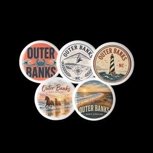 May include: Five circular pin-back buttons featuring Outer Banks, North Carolina designs. One shows a blue crab, one a hang glider, one a lighthouse, one wild horses on a beach, and one a coastal sunset with the text Outer Banks North Carolina.