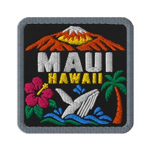 Può includere: Una toppa ricamata quadrata con sfondo nero raffigurante una montagna con la cima bianca, il testo MAUI HAWAII in bianco e giallo, un fiore di ibisco rosa, una coda di balena bianca tra onde blu e una palma verde.