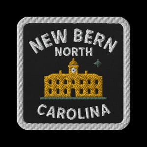 May include: Embroidered patch with the text "NEW BERN NORTH CAROLINA" in white, arched around a yellow building with a clock tower. The patch has a black background and a white border.