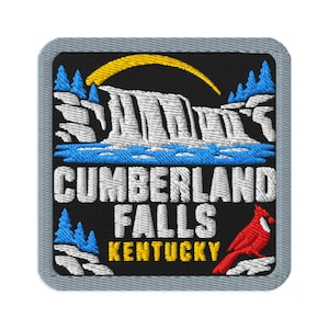Op de afbeelding: Een vierkante geborduurde patch met een grijze rand op een zwarte achtergrond, met een witte waterval, blauwe bomen, een gele zon en een rode kardinaalvogel. De tekst luidt CUMBERLAND FALLS KENTUCKY in witte en gele blokletters.