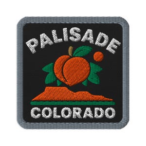 May include: A square embroidered patch with a grey border on a black background. It features the white text PALISADE at the top and COLORADO at the bottom. In the centre is an orange peach with green leaves above a stylised orange mesa.