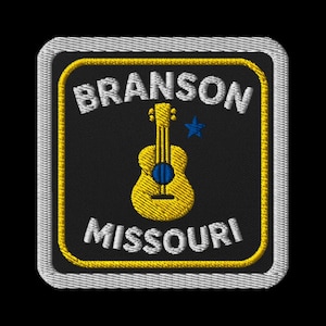 Puede incluir: Parche bordado con una guitarra amarilla, una estrella azul y las palabras "BRANSON MISSOURI" en blanco. El parche tiene un fondo negro con un borde amarillo y un borde cosido blanco. El diseño es cuadrado.