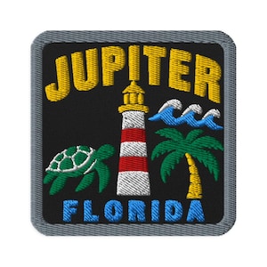 Pode incluir: Um emblema bordado quadrado com fundo preto e borda cinza. Apresenta um farol com listras vermelhas e brancas, uma tartaruga marinha verde, uma palmeira verde e ondas azuis. O texto JUPITER está em amarelo e FLORIDA está em azul.