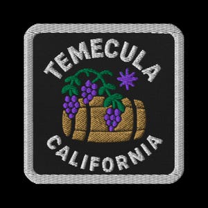 May include: Embroidered patch featuring the text "TEMECULA CALIFORNIA" in white, arched above and below a brown barrel with purple grapes and green leaves. A purple star is above the barrel. The patch has a black background and a silver border.