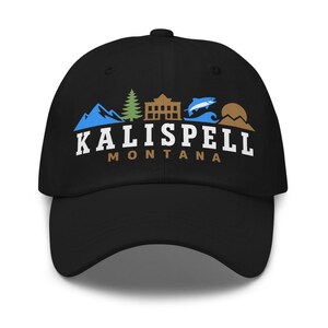 May include: A black baseball cap featuring a graphic design with blue mountains, a green pine tree, a brown building, a blue fish, and a brown sun. The text KALISPELL is printed in white, with MONTANA printed in brown underneath the graphic.