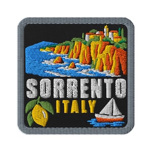 Könnte beinhalten: Ein quadratischer Stickaufnäher mit schwarzem Hintergrund zeigt eine Küstenklippe in Gelb, Orange und Grün. Unter den Klippen ist der Text SORRENTO ITALY in Weiß und Gelb gestickt, ergänzt durch eine gelbe Zitrone und ein kleines Segelboot.