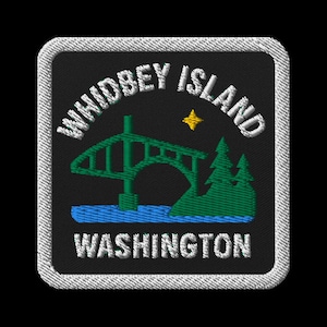 May include: Embroidered patch featuring the words "Whidbey Island Washington" in white. The design includes a green bridge over blue water, green trees, and a yellow star on a black background, framed by a white border.