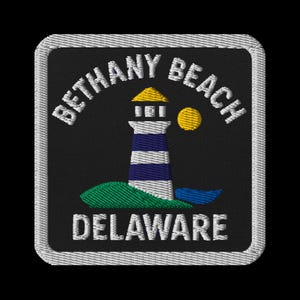 May include: Embroidered patch featuring a lighthouse with blue and white stripes, a yellow top, and a yellow sun. The patch reads "Bethany Beach Delaware" in white text against a black background, framed by a white border.