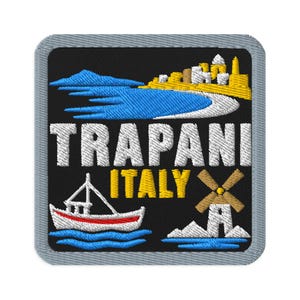 Puede incluir: Un parche bordado cuadrado con borde gris sobre fondo negro. Presenta un mar azul, una ciudad costera amarilla, un barco blanco con una franja roja, un molino de viento marrón y el texto en blanco y amarillo TRAPANI ITALY.