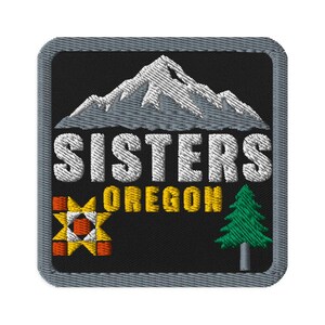 May include: A square embroidered patch with a black background and a gray border. It features a white mountain range, the text "SISTERS OREGON" in white and yellow, a colorful geometric quilt block pattern, and a green pine tree with a gray trunk.