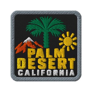 Könnte beinhalten: Ein quadratischer gestickter Aufnäher mit schwarzem Hintergrund und grauem Rand. Das Design zeigt eine grüne Palme, einen orangefarbenen Berg mit weißer Schneekuppe und eine gelbe Sonne. Der Text lautet PALM DESERT in Gelb und CALIFORNIA in Weiß.