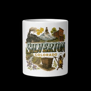 May include: White ceramic mug featuring a vintage illustration of Silverton, Colorado. The design includes a steam train, mountain, buildings, and the text "Silverton Colorado". A charming souvenir or gift.