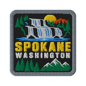 May include: A square embroidered patch with a black background featuring a waterfall, green pine trees, a yellow sun, and orange mountains. The text SPOKANE is in yellow and WASHINGTON is in white. The patch has a gray border and rounded corners.