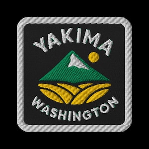 May include: Embroidered patch featuring the text "YAKIMA WASHINGTON" in white, arched over and under a green mountain and yellow fields design, with a yellow sun. The patch has a black background and a white border.
