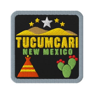 Puede incluir: Un parche bordado cuadrado con fondo negro y borde gris. Presenta colinas desérticas amarillas, una estrella blanca y cuatro estrellas amarillas más pequeñas. El texto TUCUMCARI NEW MEXICO está bordado en amarillo y verde. Incluye un tipi y un cactus.