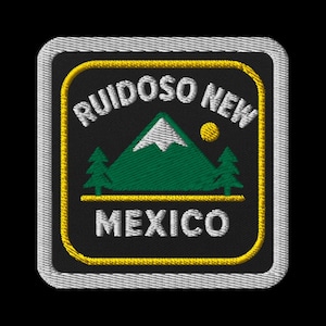 May include: Embroidered patch featuring the text "RUIDOSO NEW MEXICO" in white, with a green mountain, two green trees, and a yellow sun. The patch has a black background with a yellow border and a gray stitched edge.