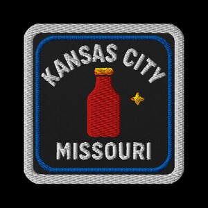 May include: Embroidered patch featuring "Kansas City Missouri" in white text. A red bottle with a gold cap and a gold star are centered on a black background. The patch has a blue border and a white stitched edge.