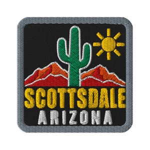 Może przedstawiać: Kwadratowa naszywka z czarnym tłem przedstawiająca zielony kaktus saguaro, pomarańczowe góry i żółte słońce. Napis SCOTTSDALE jest wyhaftowany na żółto, a ARIZONA na biało poniżej, całość wykończona szarą obwódką.