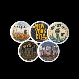 May include: A set of five circular buttons featuring New York City imagery. Designs include a skyline with a water tower, a yellow taxi, the Statue of Liberty, the Brooklyn Bridge in gold lines, and a sunset cityscape, all labeled New York City.