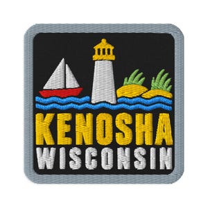 May include: A square embroidered patch with a black background and a grey border. It features a white lighthouse, a red and white sailboat, and yellow islands with green grass above blue waves. The text KENOSHA WISCONSIN is stitched in yellow and white.