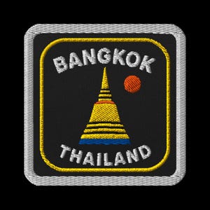 May include: Embroidered patch featuring the words "BANGKOK" and "THAILAND" in white, arched over and under a gold and blue pagoda. A small orange circle is to the right of the pagoda. The patch has a black background and a silver border.