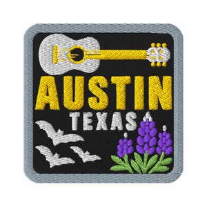 May include: A square embroidered patch with a black background and a gray border. It features a white acoustic guitar, the yellow text AUSTIN, white text TEXAS, three white bats in flight, and a cluster of purple bluebonnet flowers with green leaves.