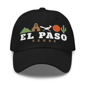 May include: A black baseball cap featuring a graphic design with a green mountain, a brown mission building, a white roadrunner, an orange sun, and a green cactus. The text EL PASO is printed in large white letters with the word TEXAS in smaller brown letters.