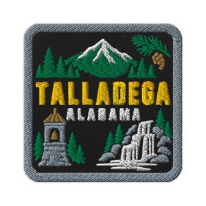 May include: A square embroidered patch with a black background featuring a green mountain with white snow, a pine branch, a stone bell tower, and a waterfall. The text TALLADEGA is in yellow, and ALABAMA is in white, all bordered by a grey stitched edge.