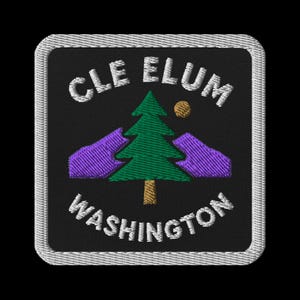 Puede incluir: Parche bordado con el texto "CLE ELUM WASHINGTON" en blanco, sobre un pino verde, un sol amarillo y montañas moradas sobre un fondo negro. El parche tiene un borde blanco.