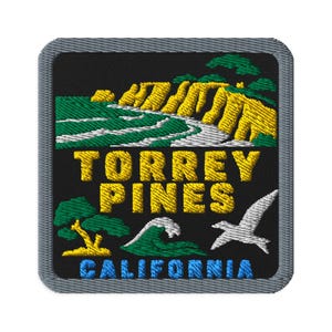 May include: A square embroidered patch with a gray border featuring a black background. The design depicts yellow cliffs, green trees, a white wave, and a white bird. The text reads TORREY PINES in yellow and CALIFORNIA in blue lettering.
