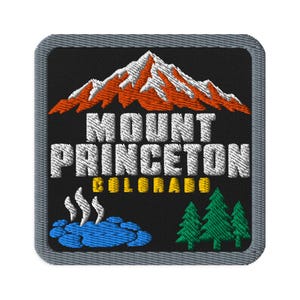 May include: A square embroidered patch with a black background featuring a white and orange mountain peak above the white text MOUNT PRINCETON and yellow text COLORADO. Below, a blue hot spring with white steam and three green pine trees.