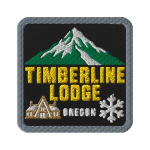 Puede incluir: Un parche bordado cuadrado con fondo negro y borde gris. Presenta un pico de montaña verde y blanco sobre el texto amarillo "TIMBERLINE LODGE". Debajo del texto hay un pequeño edificio marrón, la palabra "OREGON" y un copo de nieve blanco.