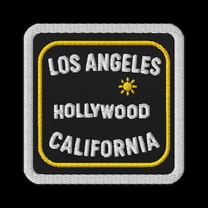 Könnte beinhalten: Gestickter Aufnäher mit schwarzem Hintergrund, mit den Wörtern "LOS ANGELES", "HOLLYWOOD" und "CALIFORNIA" in Weiß. Zwischen den ersten beiden Zeilen befindet sich eine gelbe Sonnengrafik. Der Aufnäher hat einen gelben Rand und einen weiß genähten Rand.