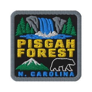Peut inclure: Un écusson brodé carré avec un fond noir et une bordure grise. Le motif représente une cascade bleue, des pins verts, une montagne verte, le contour d'un ours blanc et le texte jaune PISGAH FOREST avec N. CAROLINA écrit en bleu.