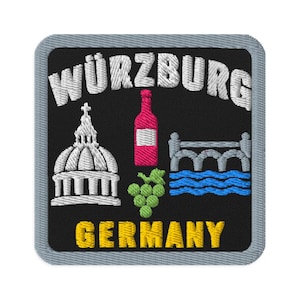 May include: A square embroidered patch with a black background and a grey border. It features the white text WÜRZBURG at the top and GERMANY in yellow at the bottom. The design includes a white building, a red wine bottle, green grapes, and a bridge.
