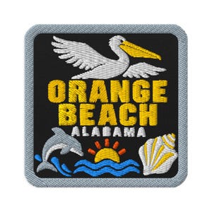 May include: A square embroidered patch with a black background and a light gray border. It features a white pelican with a yellow beak, the yellow text ORANGE BEACH, white text ALABAMA, a gray dolphin, a yellow sun, blue waves, and a white seashell.