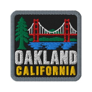 May include: A square embroidered patch with a grey border on a black background. It features a green pine tree, a red suspension bridge, and blue water. The text OAKLAND is in white capital letters, and CALIFORNIA is in yellow capital letters.