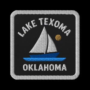 May include: Embroidered patch featuring a sailboat on blue water, with a gold sun. The text "LAKE TEXOMA OKLAHOMA" is arched above and below the image. The patch has a black background and a white border.