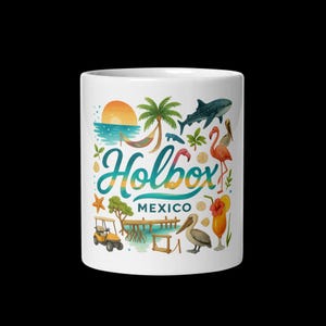 Pode incluir: Uma caneca de cerâmica branca com uma alça preta e o texto "But First, Coffee" em negrito preto. A caneca está sobre um fundo desfocado, sugerindo um ambiente acolhedor.