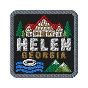 May include: A square embroidered patch with a black background and a grey border. It features a white and red timber-framed house, green pine trees, blue water waves with a white inner tube, and green mountains. The text reads HELEN GEORGIA.