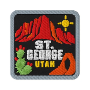 May include: A square embroidered patch with a black background featuring red and orange mountain silhouettes, a yellow sun, a green prickly pear cactus with red fruit, and a natural orange rock arch. The text reads ST. GEORGE UTAH in white and yellow.