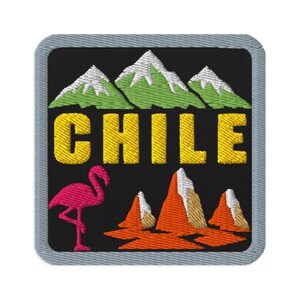May include: A square embroidered patch with a gray border on a black background. It features green mountains with white peaks, the yellow text CHILE, a pink flamingo, and orange rock formations with white accents at the base of the design.